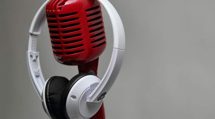 Red vintage microphone with white headphones against a grey background